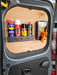 The interior of a vehicle door features a wall-mounted, space-saving Aerosol Can Holder with a small shelf holding various aerosol cans and a box of disposable gloves attached to the wooden panel.