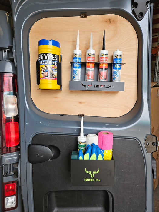 The interior door of a van features a well-organized storage system with wall-mounted compartments, showcasing van accessories like a General Purpose Metal Storage Box - Medium, various sealant tubes, spray cans, and other essential cleaning supplies.