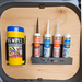 A container of Big Wipes and four tubes of sealants and fillers are organized in a high-quality construction, space-saving design wall-mounted Silicone Mastic Holder inside a workspace.